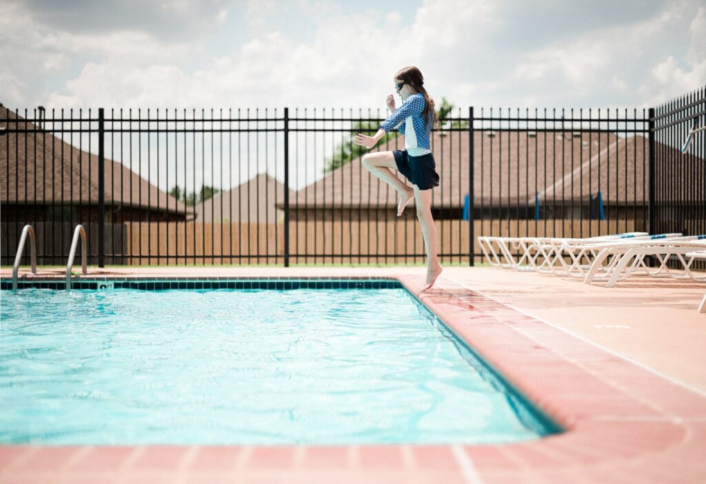 Girl jumps into the deep end of the pool on a cloudy summer day