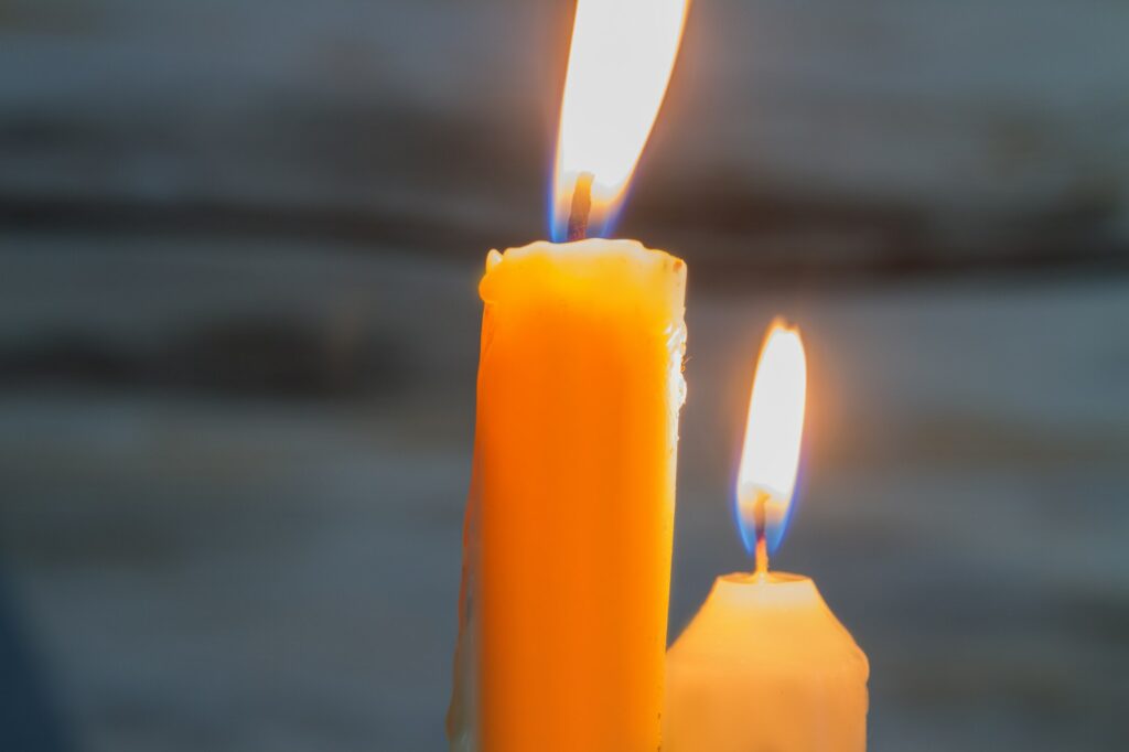 Two yellow burning candles closeup.